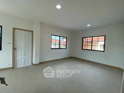 Spacious empty room with large windows and tiled flooring in modern home.