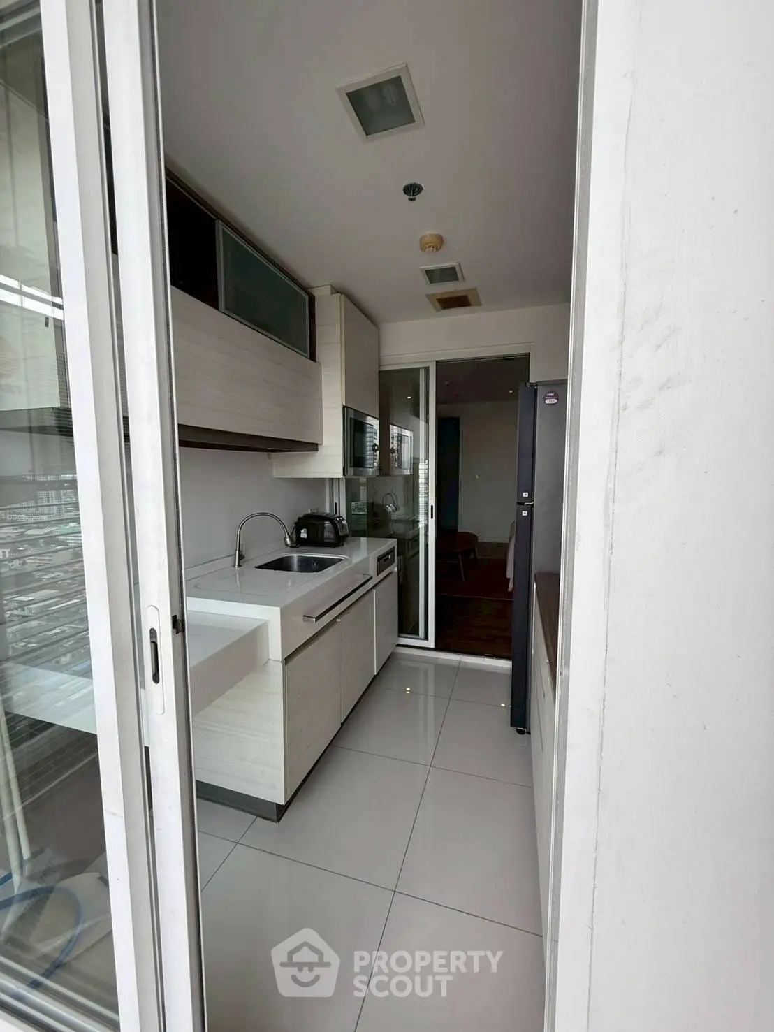 Modern compact kitchen with sleek cabinetry and appliances in a high-rise apartment.