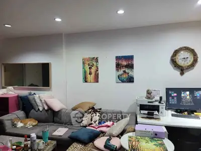 Cozy living room with modern decor, featuring a comfortable sofa, wall art, and a home office setup.