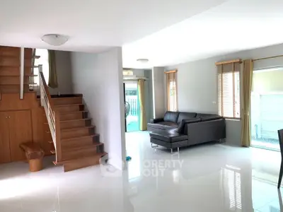 Spacious modern living room with sleek staircase and natural light