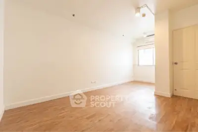 Spacious empty room with wooden flooring and bright natural light