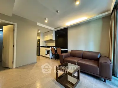 Modern living room with open kitchen, stylish furniture, and natural light.