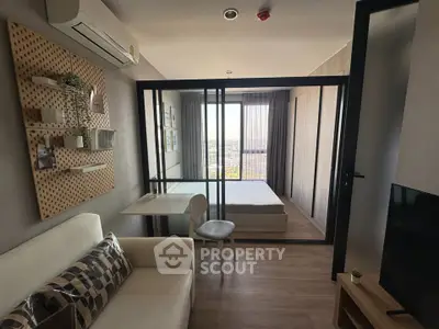 Modern studio apartment with glass partition, cozy living area, and city view.