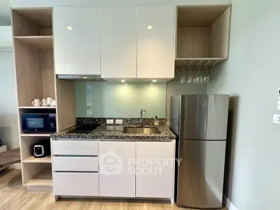 Modern kitchen with sleek cabinets, granite countertop, and stainless steel fridge