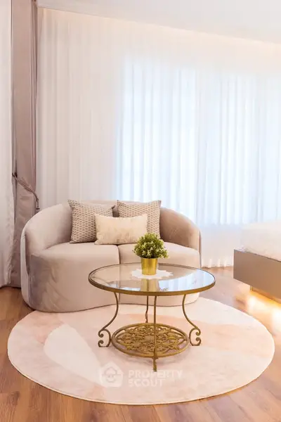 Elegant living room with plush sofa, round glass coffee table, and soft lighting for a cozy ambiance.