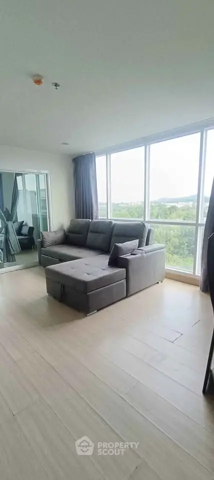Spacious living room with large windows and modern gray sofa, offering abundant natural light and scenic views.