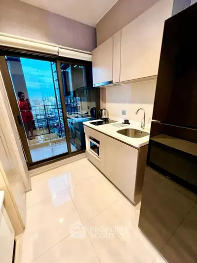 Modern kitchen with sleek design and balcony view in high-rise apartment