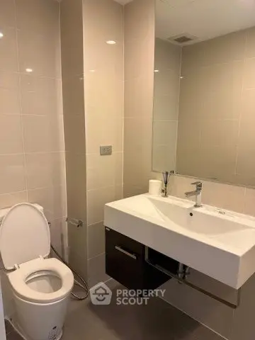 Modern bathroom with sleek fixtures and large mirror in a contemporary apartment.