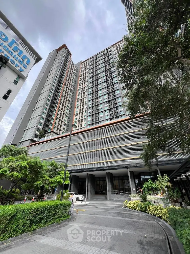 Modern high-rise building with lush greenery and spacious entrance