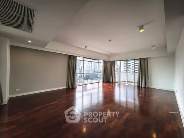 Spacious modern living room with hardwood floors and city view balcony.