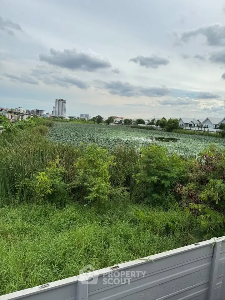 Scenic view of lush greenery and serene water body with distant cityscape, perfect for tranquil living.