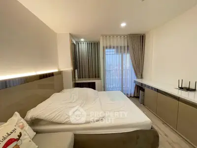 Modern bedroom with large window and sleek furnishings in a high-rise apartment.