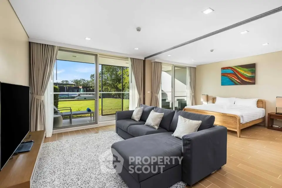 Spacious modern living room with large windows and garden view, featuring a cozy sofa and elegant decor.