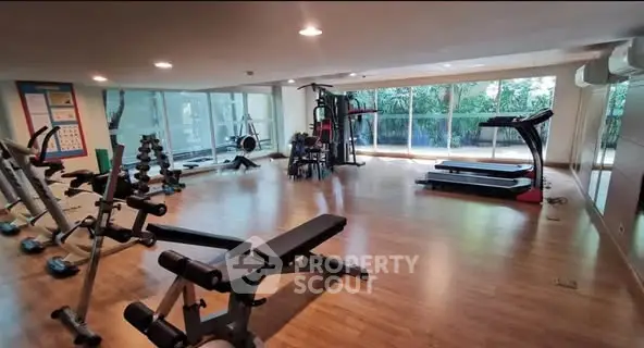 Spacious gym with modern equipment and large windows in luxury property.