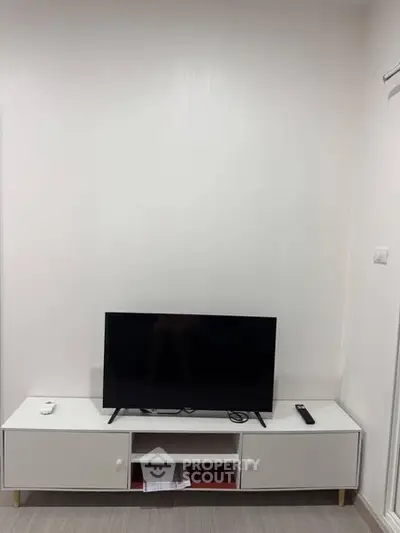 Modern minimalist living room with sleek TV stand and flat-screen TV.