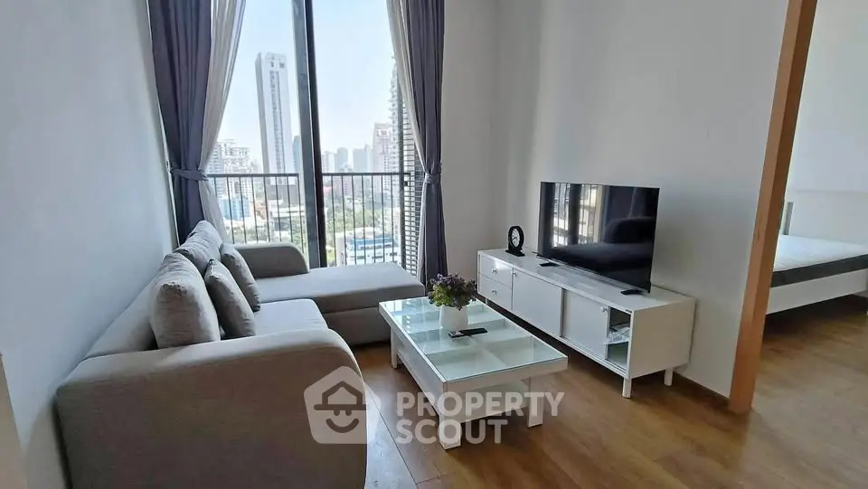 Modern living room with city view, featuring sleek furniture and large windows for natural light.