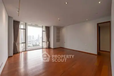 Spacious empty living room with wooden floors and city view, perfect for customization.