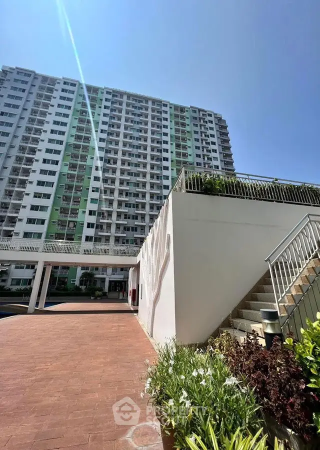 High-rise residential building with sunny exterior and landscaped entrance.