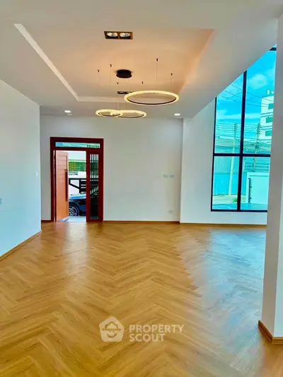 Spacious modern living room with elegant lighting and large windows offering natural light.