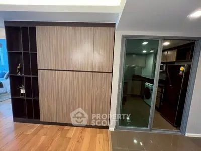 Modern apartment interior with sleek kitchen and laundry area, featuring stylish wood paneling and glass sliding door.