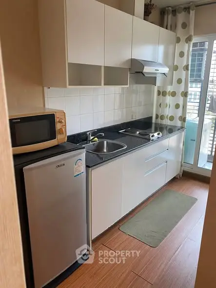 Modern compact kitchen with sleek cabinetry and appliances in a bright apartment.