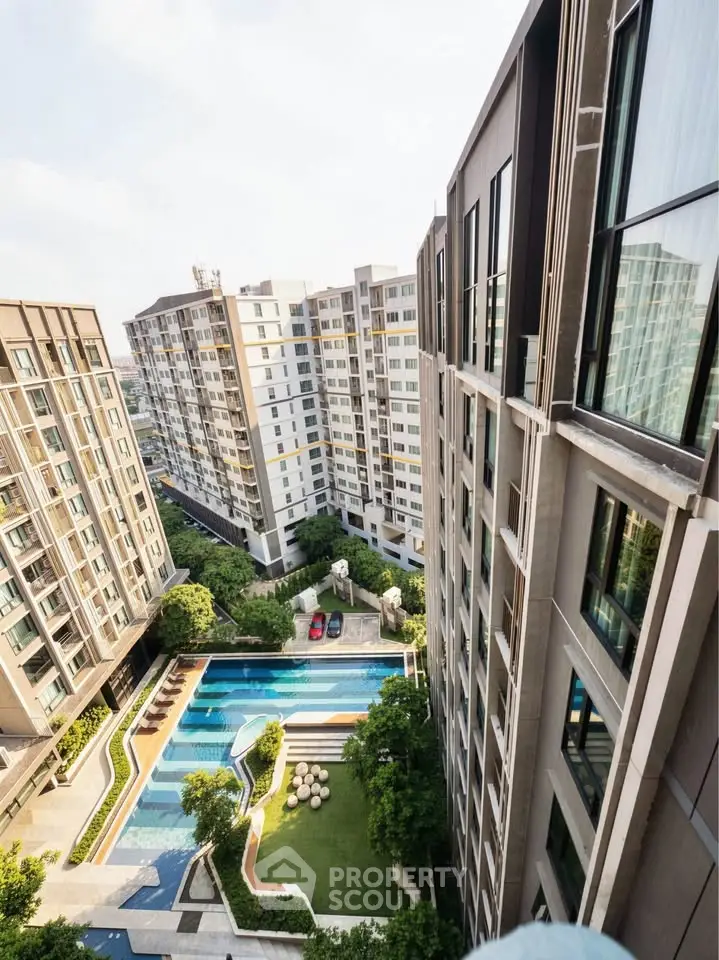 Stunning aerial view of modern apartment complex with pool and lush greenery.