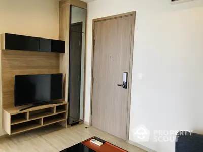 Modern compact living room with sleek built-in entertainment unit, flat-screen TV, and wooden door, ideal for urban living.