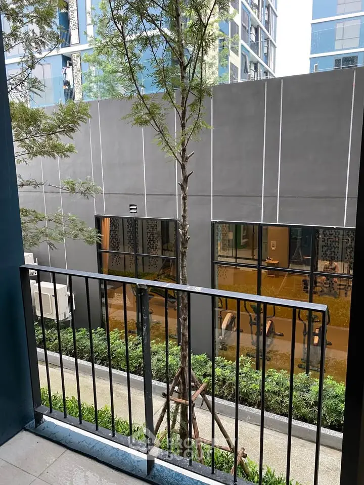Modern apartment balcony with garden view and sleek building exterior.