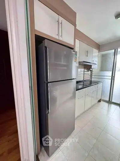 Modern kitchen with sleek stainless steel fridge and white cabinetry