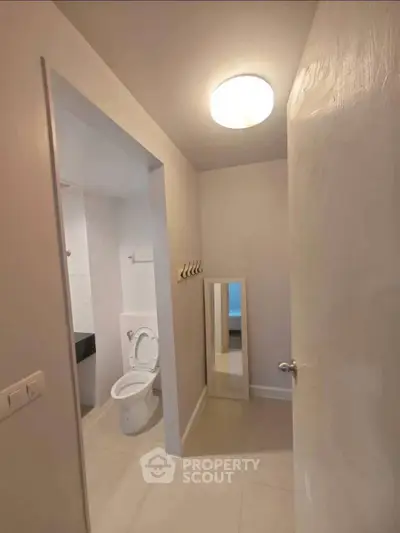 Modern bathroom with sleek design and neutral tones, featuring a toilet and mirror.