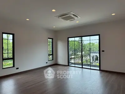 Spacious empty living room with large windows and balcony view.