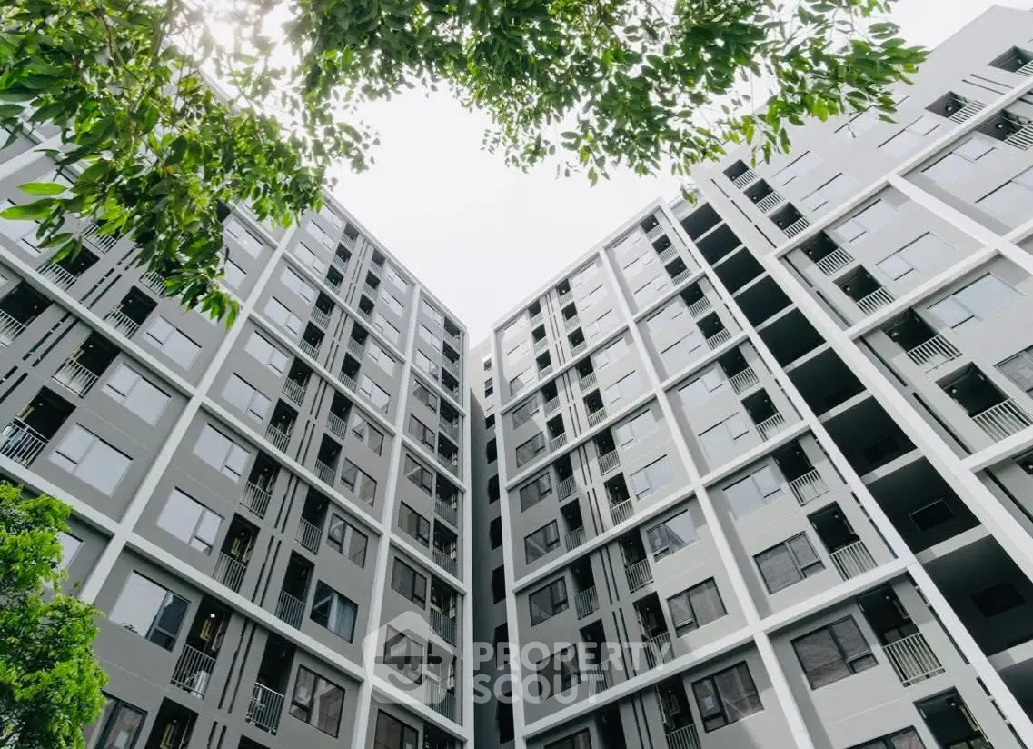 Modern high-rise apartment building with lush greenery and sleek design.