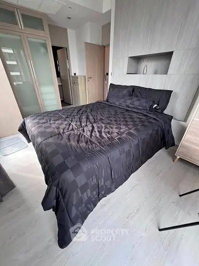 Modern bedroom with sleek design and stylish bedding in a contemporary apartment.