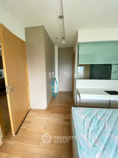 Modern bedroom with wooden flooring and built-in wardrobe, featuring a cozy bed and sleek design.