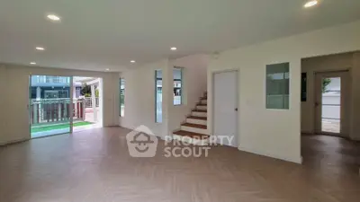 Spacious modern living room with wooden flooring and staircase in a bright open layout home.