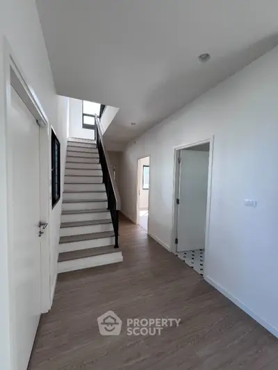 Modern hallway with wooden flooring and staircase in a bright home interior