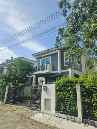 Charming two-story house with lush greenery and modern design in a serene neighborhood.