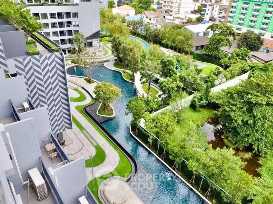 Stunning aerial view of modern residential complex with lush gardens and winding pool.