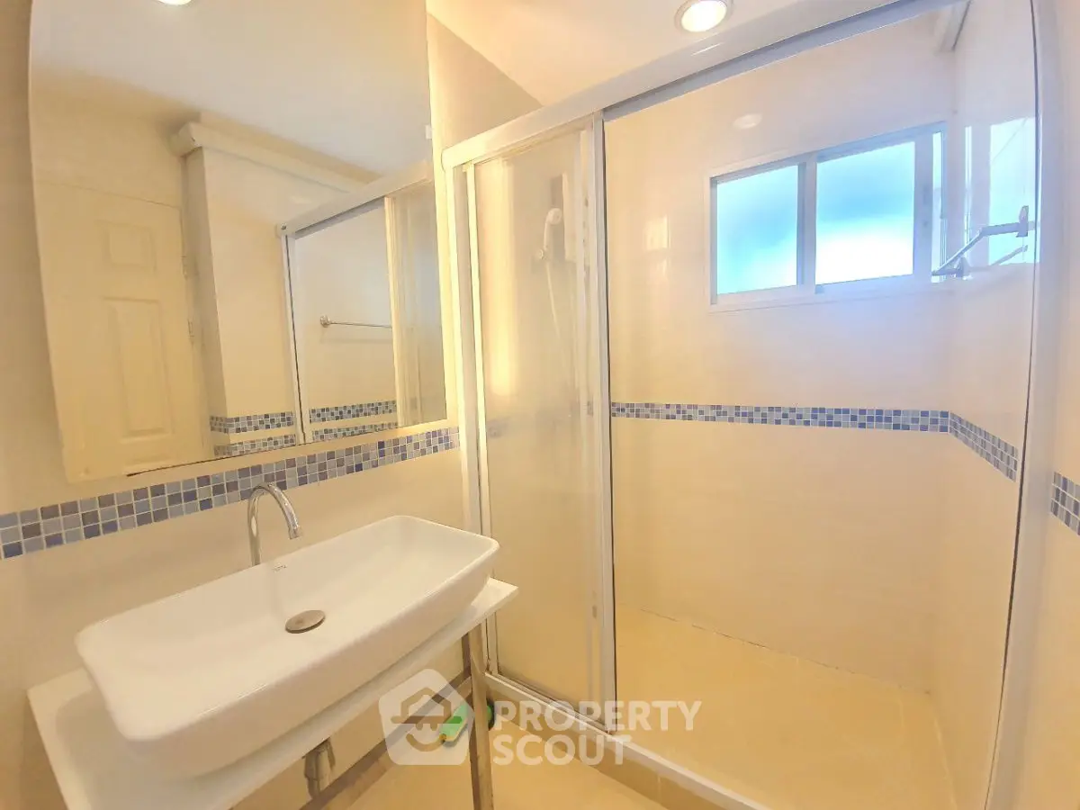 Modern bathroom with glass shower and stylish sink in bright lighting.