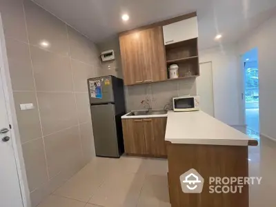 Modern kitchen with sleek cabinetry and stainless steel fridge in a cozy apartment