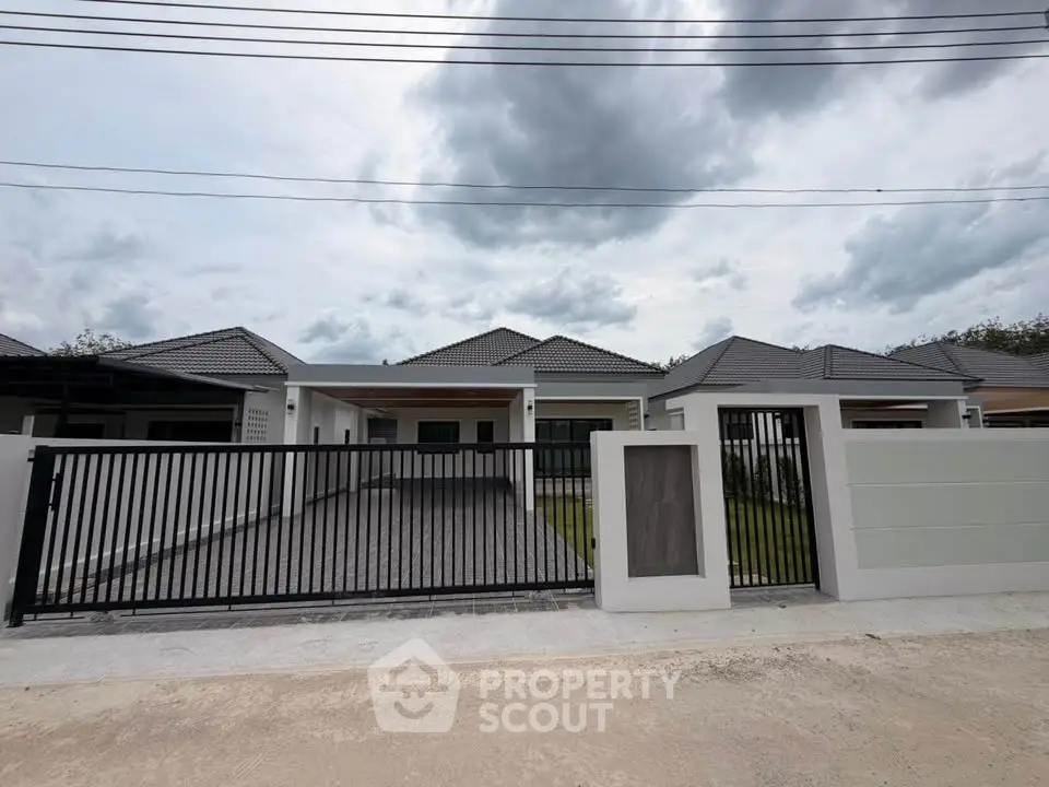 Modern single-story house with gated driveway and contemporary design.