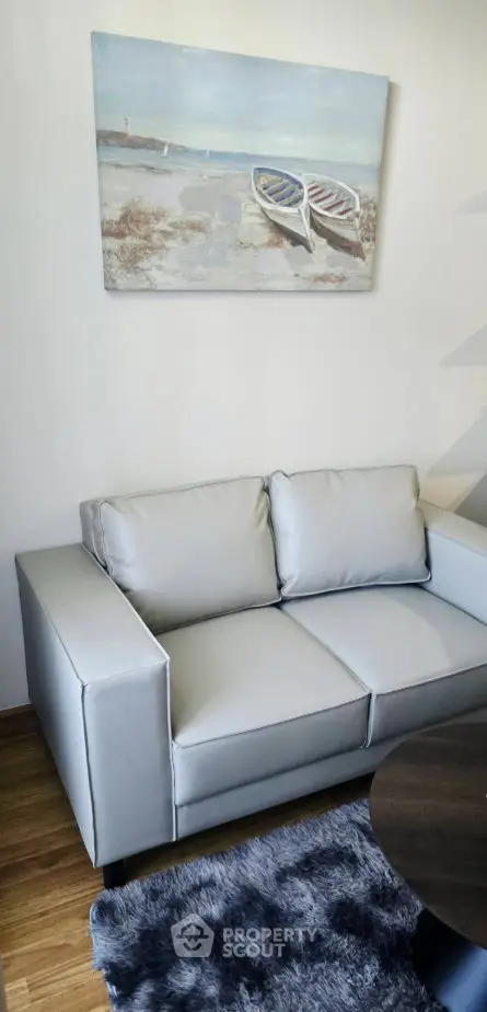 Modern living room with sleek gray sofa and nautical wall art, perfect for stylish urban living.