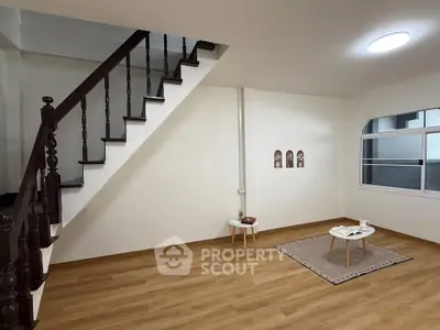 Spacious living room with wooden flooring and elegant staircase in modern home.