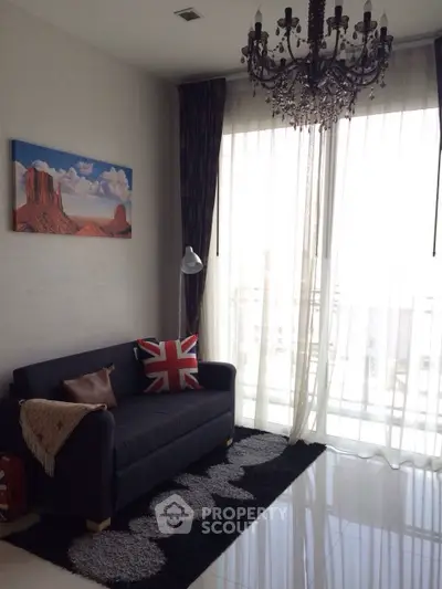 Stylish living room with chandelier and large window, featuring modern decor and natural light.