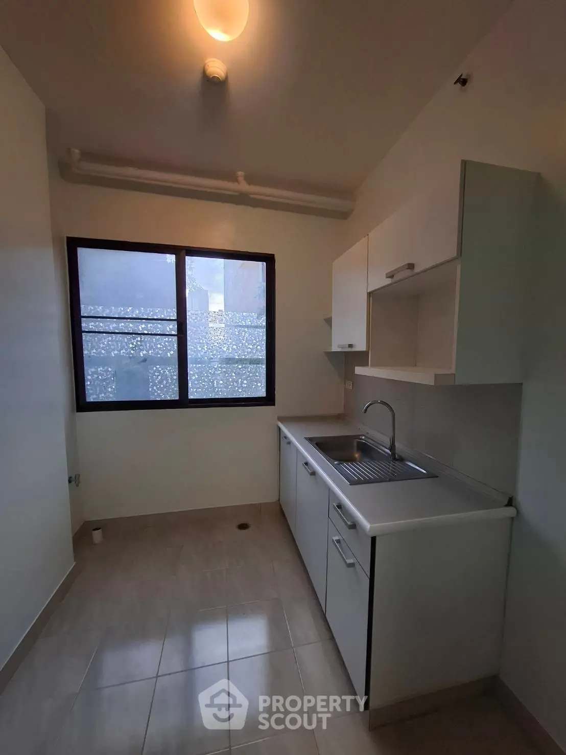 Compact kitchen with modern cabinetry and large window for natural light