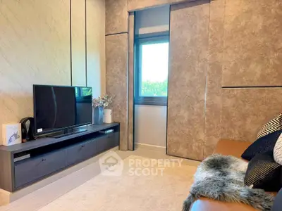 Modern living room with sleek TV unit and cozy decor, featuring a large window with natural light.