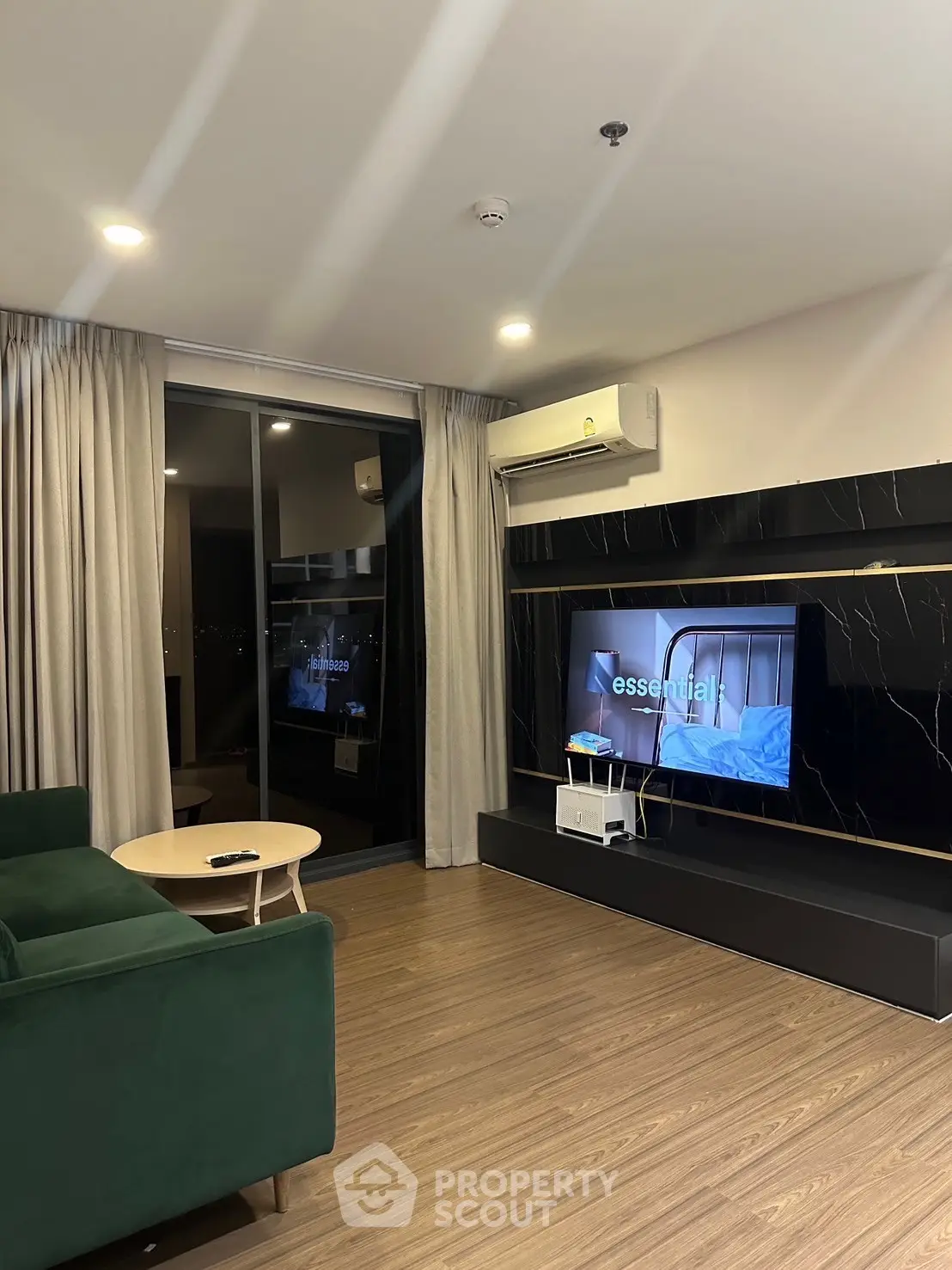 Modern living room with sleek design, featuring a large TV and stylish furniture, perfect for relaxation.