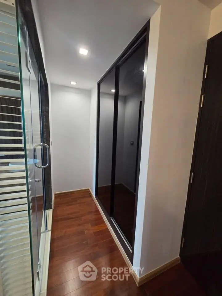 Modern hallway with wooden flooring and glass door, perfect for contemporary living spaces.