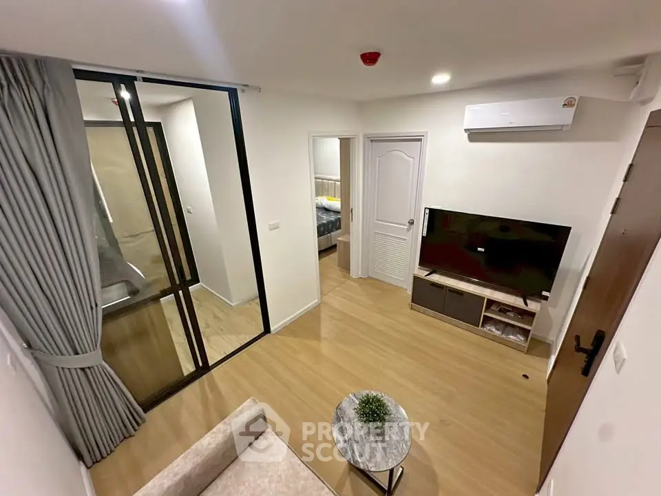 Modern living room with sleek design, featuring a large TV, air conditioning, and stylish decor.