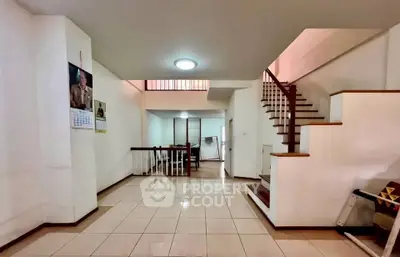 Spacious open-plan living area with staircase and tiled flooring in modern home.